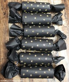 several rolls of black and gold patterned paper on a wooden floor with bags around them