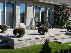 a patio with stone steps and potted plants on the side of it in front of a house