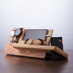 a wooden stand with two cell phones, sunglasses and wallet on it's side