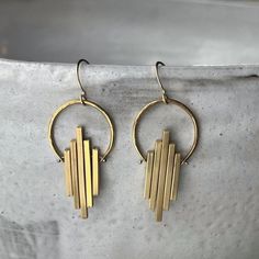 "These art deco dangles are clean and classy with a graceful swing to them, making them a perfect accessory for your dinner party or a dressy night out with the girls!  Using just a few spools of wire, some brass pieces, and a collection of specialized tools, we hammer, drill, melt, sand, and polish each individual piece until it becomes a wearable work of art. The 14k gold fill ear wires provide a luxurious touch and attach to a solid brass hand textured semi-circle. Below the circle, varying l Kinetic Earrings, Bible Design, Cool Earrings, Raw Stone Earring, Bar Metal, Deco Earrings, Earrings Art, Hammer Drill, Statement Earring