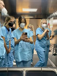 medical personnel in scrubs are looking at their cell phones while wearing facemasks