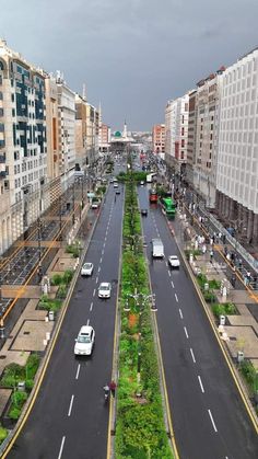 an aerial view of a city street with cars driving on the road and tall buildings in the background