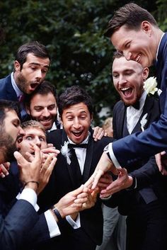 a group of men in tuxedos are all holding hands together