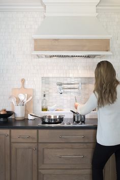 a woman standing in front of a stove preparing food