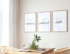 a dining room table with chairs and two framed pictures on the wall above it,