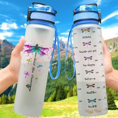 two water bottles with dragonflys on them are held up in front of the camera