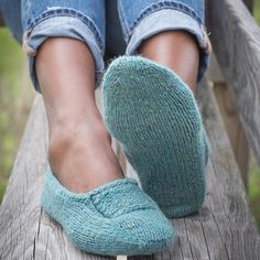 a person sitting on a wooden bench with their feet propped up against the railing wearing blue socks