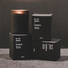 three black boxes stacked on top of each other with one candle in front of them