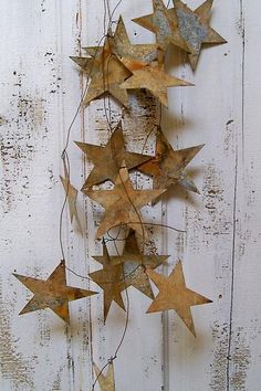 some metal stars are hanging on a white wooden wall and there is no image to describe