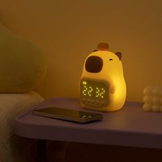 an alarm clock sitting on top of a table next to a cell phone and candles