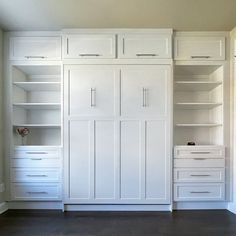 an empty room with white cabinets and drawers