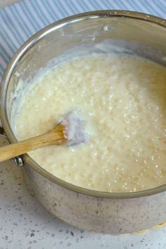 a wooden spoon in a metal pot filled with liquid on top of a white counter