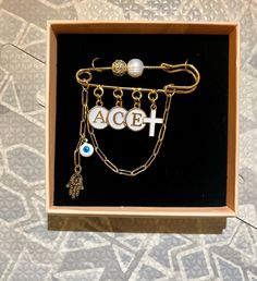 an open box with two necklaces and a cross on the inside, sitting on a patterned surface