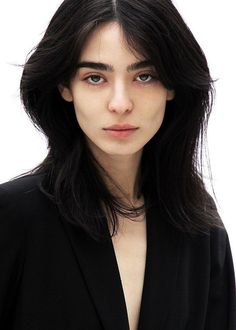 a woman with long black hair is posing for the camera and looking at the camera