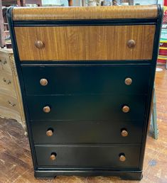 a black dresser with wooden drawers and knobs on it's sides in a store