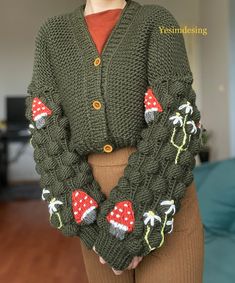 a woman wearing a green knitted cardigan with mushrooms on the sleeves and buttons