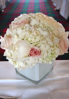 a bouquet of white and pink flowers in a vase on a table with red carpet