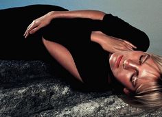 a woman laying down on top of a rock