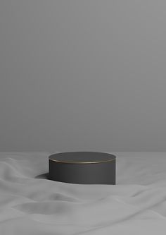 a round black object sitting on top of a white tablecloth covered ground with waves