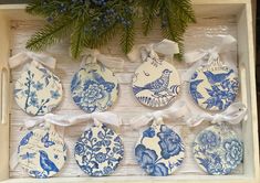 six blue and white plates in a box with ribbon tied around the edges, sitting on a shelf