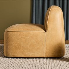 a tan leather chair sitting on top of a carpeted floor next to a window