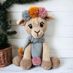 a knitted stuffed animal sitting next to a potted plant on a white wooden surface