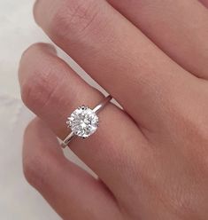 a woman's hand with a diamond ring on top of her finger, showing the center stone