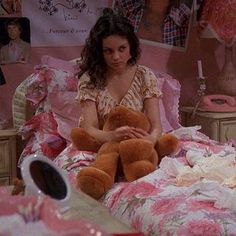 a woman sitting in bed holding a teddy bear