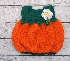 a crocheted pumpkin purse sitting on top of a white wooden floor with a flower in the center