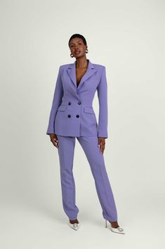 a woman is wearing a purple suit and white shoes with her hands on her hips