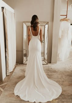 a woman standing in front of a mirror wearing a white dress