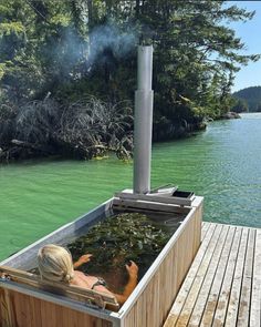 a woman sitting in a hot tub on top of a wooden dock