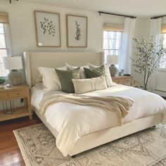 a large white bed sitting in a bedroom next to two windows