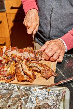 a person cutting meat on top of a wooden cutting board