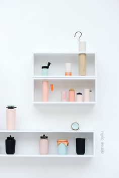 three white shelves with different types of cups and containers on them, one is empty