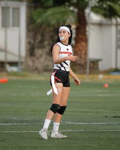 a female soccer player is standing on the field with her ball in her mouth and wearing knee pads