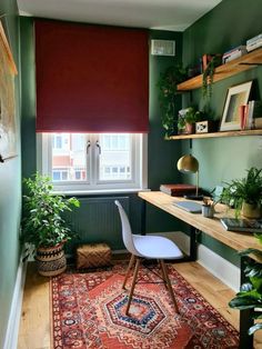 a room with green walls and a rug on the floor next to a desk, bookshelf and window