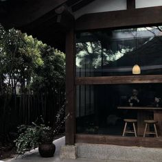 a person sitting at a table in front of a glass window with trees behind it