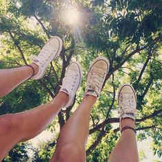 two people standing in front of a tree with their feet up and one person wearing white shoes