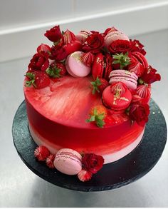 a heart shaped cake decorated with roses and macaroons on a black platter