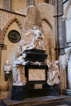 a statue in the middle of a church with statues around it and writing on the wall