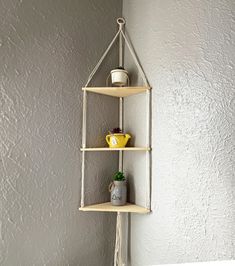 three shelves with pots and vases on them hanging from the side of a wall