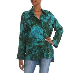 Designed by Galuh Kenanga this beautiful blouse showcases hand-stamped batik in teal and turquoise. She works in rayon for the long-sleeved shirt with its hi-low hem. The shirt closes with coconut shell buttons. Green Casual Tops With Batik Print, Blue Long Sleeve Top With Batik Print, Casual Green Batik Print Top, Long Sleeve Batik Print Top With Relaxed Fit, Long Sleeve Tops With Batik Print And Relaxed Fit, Long Sleeve Relaxed Fit Batik Print Tops, Relaxed Fit Long Sleeve Tops With Batik Print, Green Rayon Long Sleeve Tops, Green Long Sleeve Rayon Top