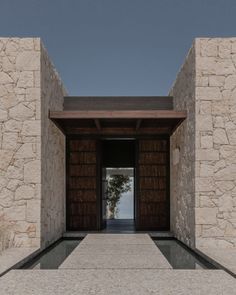 an entrance to a building with stone walls and wooden doors on both sides, leading into the outside