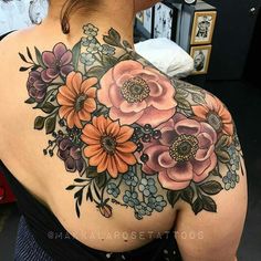 a woman's back tattoo with flowers on her shoulder and the upper half of her body