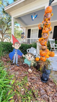 halloween decorations in front of a house with scarecrows and pumpkins on the ground