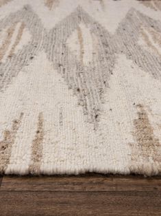 a white and brown rug on top of a wooden floor