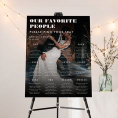 a black and white poster on a tripod next to a vase with flowers in it