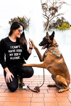 a woman kneeling down next to a dog with its paw on another dog's leg