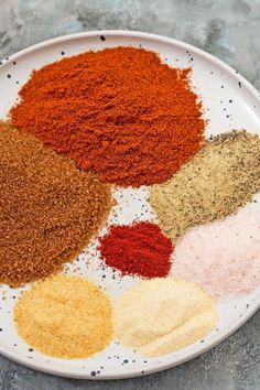 several different types of spices on a white plate